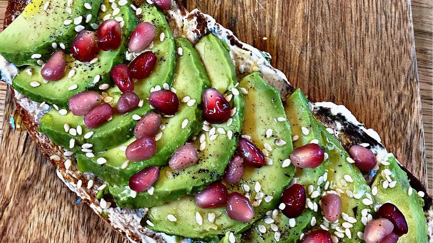 Avocado toast aux graines de grenade et sésame, sur planche en bois