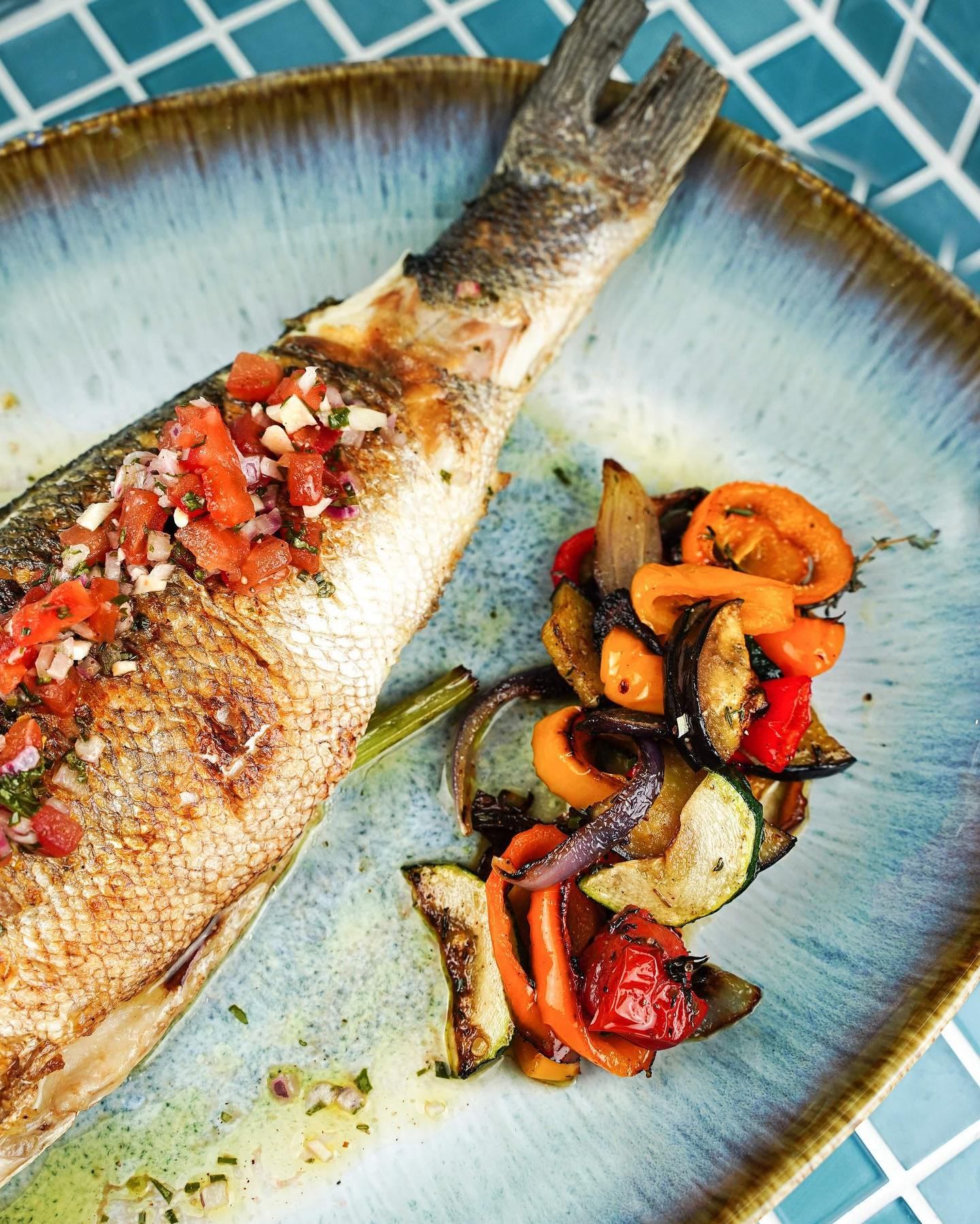 Poisson entier grillé, servi sur la mosaïque turquoise