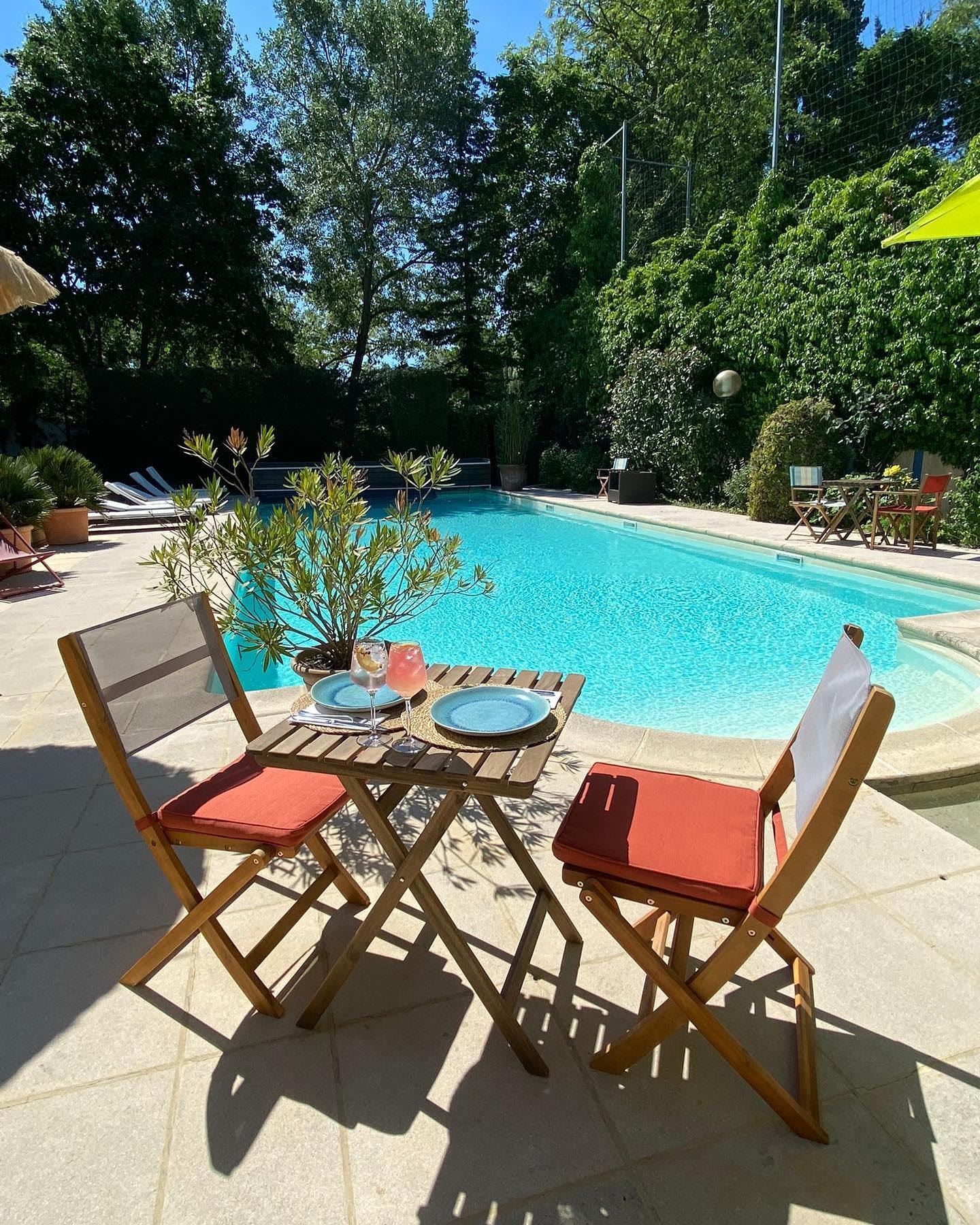Table et chaises au bord du bassin, en plein soleil