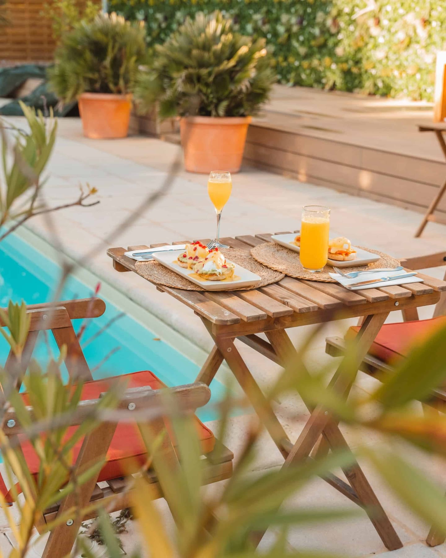 Table dressée au bord de la piscine, pancakes et jus d'orange